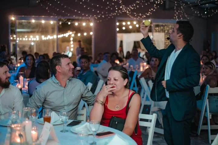 Invitados riéndose en una fiesta con guirnaldas de luces