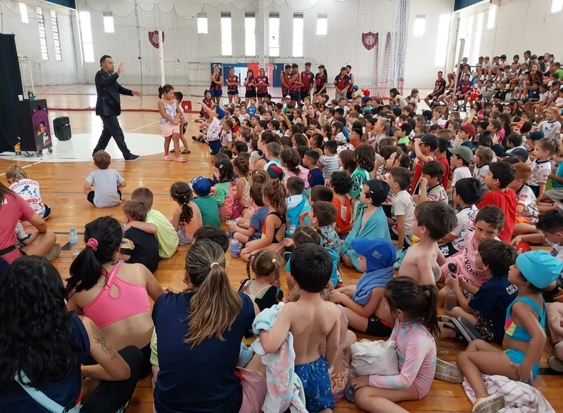 Un gimnasio lleno de chicos sentados mirando el show