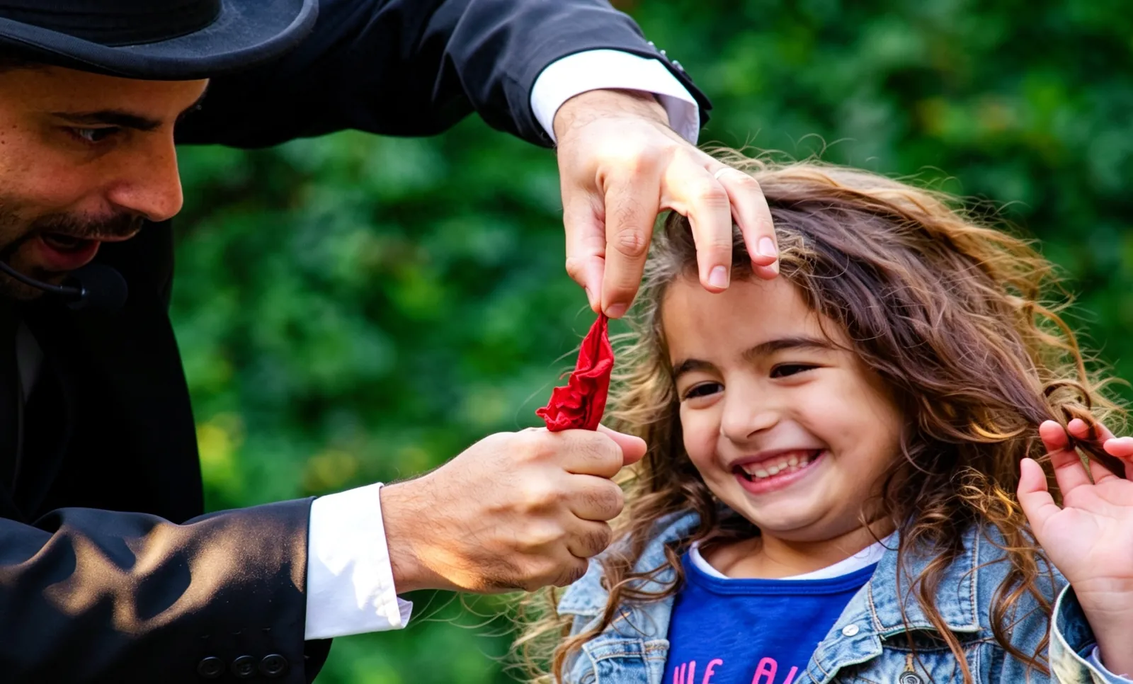 Una nena se ríe mientras Komodín le saca un pañuelo rojo del pelo